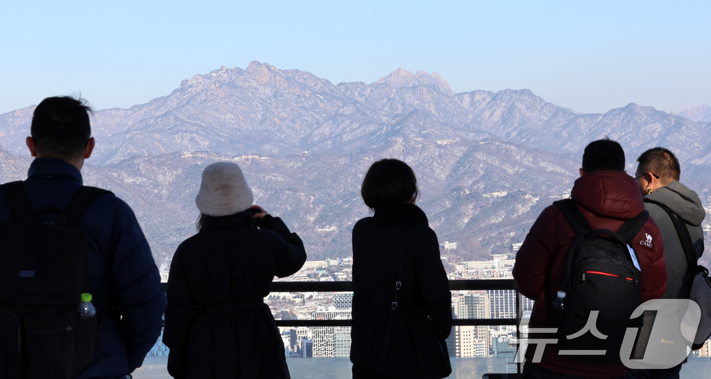 (서울=뉴스1) 구윤성 기자 = 5일 오전 서울 남산을 찾은 외국인 관광객들이 눈이 쌓인 북한산을 바라보고 있다. 2025.12.5/뉴스1