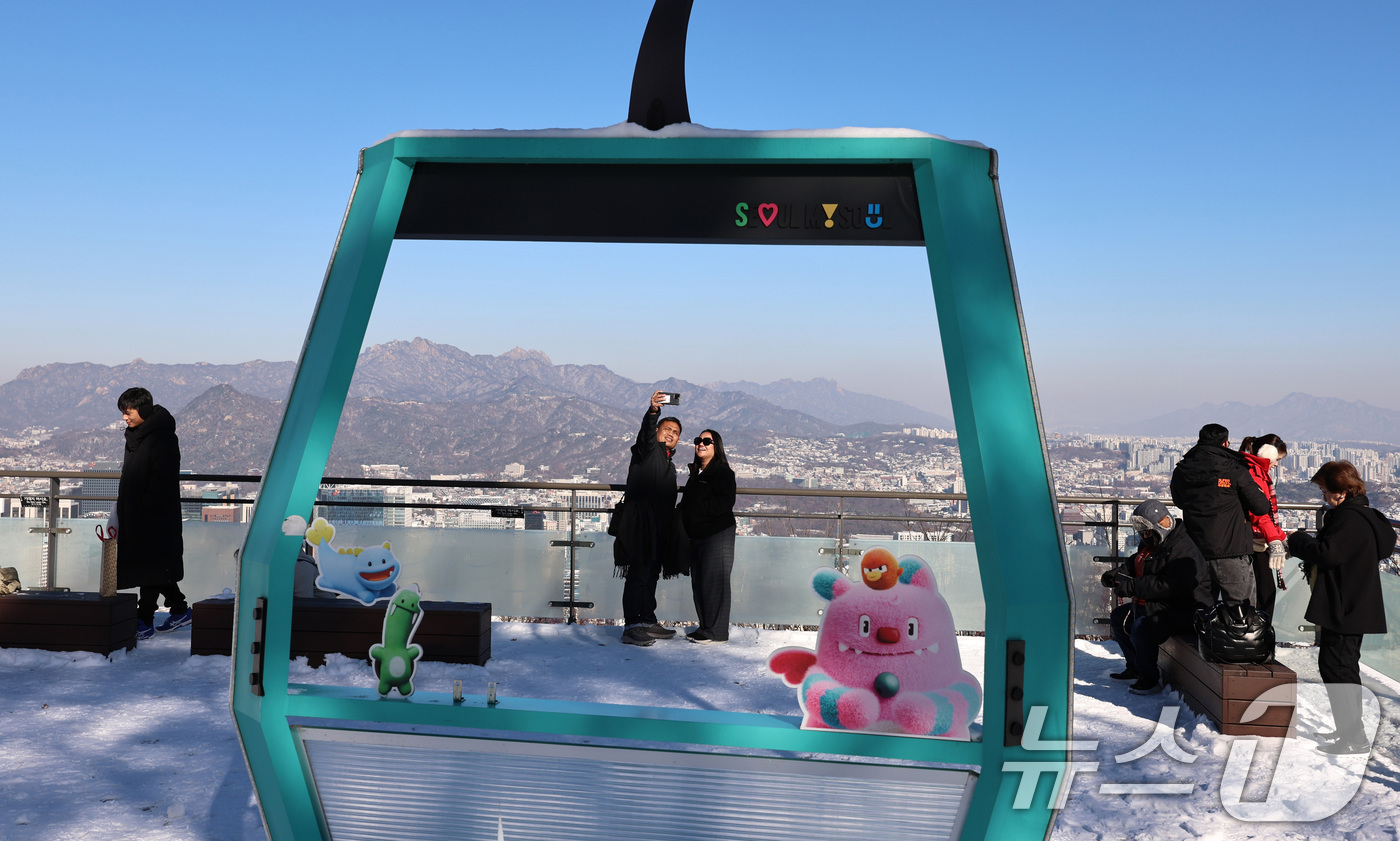 (서울=뉴스1) 구윤성 기자 = 5일 오전 서울 남산을 찾은 외국인 관광객들이 전날 내린 눈을 배경으로 스마트폰 셀카를 찍고 있다. 2025.12.5/뉴스1