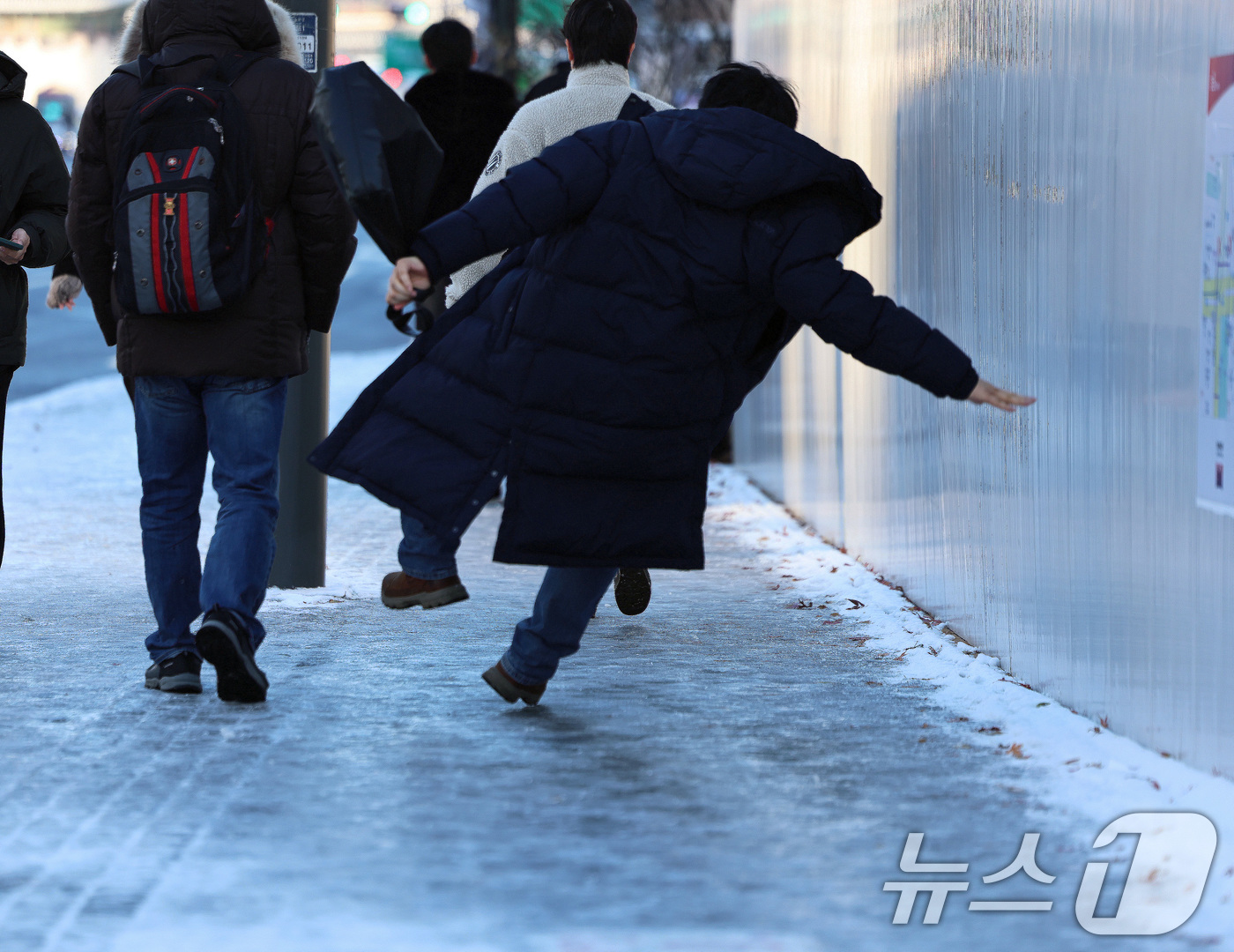 (서울=뉴스1) 구윤성 기자 = 폭설 후 한파로 도로 곳곳이 얼어붙은 5일 오전 서울 광화문역 일대에서 한 시민이 빙판길에 미끄러져 넘어지고 있다. 2025.12.5/뉴스1