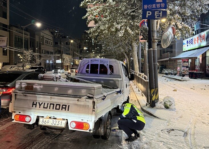 본문 이미지 - 기습적인 폭설이 내린 4일 밤, 동대문경찰서 소속 경찰관이 눈길에 멈춰선 트럭에 안전 조치를 취하고 있다./동대문경찰서 제공