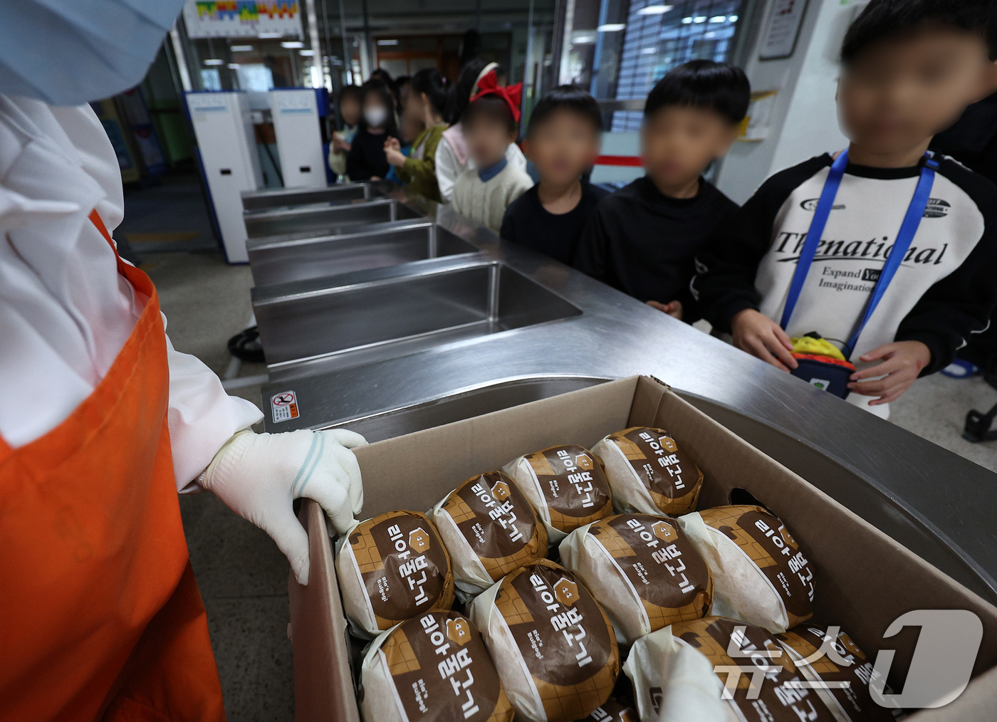 (대구=뉴스1) 공정식 기자 = 전국학교비정규직연대회의가 파업에 들어간 5일 대구의 한 초등학교 급식실에서 학생들이 대체식으로 제공된 햄버거를 받고 있다. 2025.12.5/뉴스1 …