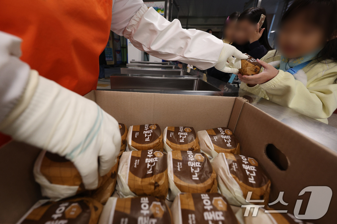 (대구=뉴스1) 공정식 기자 = 전국학교비정규직연대회의가 파업에 들어간 5일 대구의 한 초등학교 급식실에서 학생들이 대체식으로 제공된 햄버거를 받고 있다. 2025.12.5/뉴스1 …