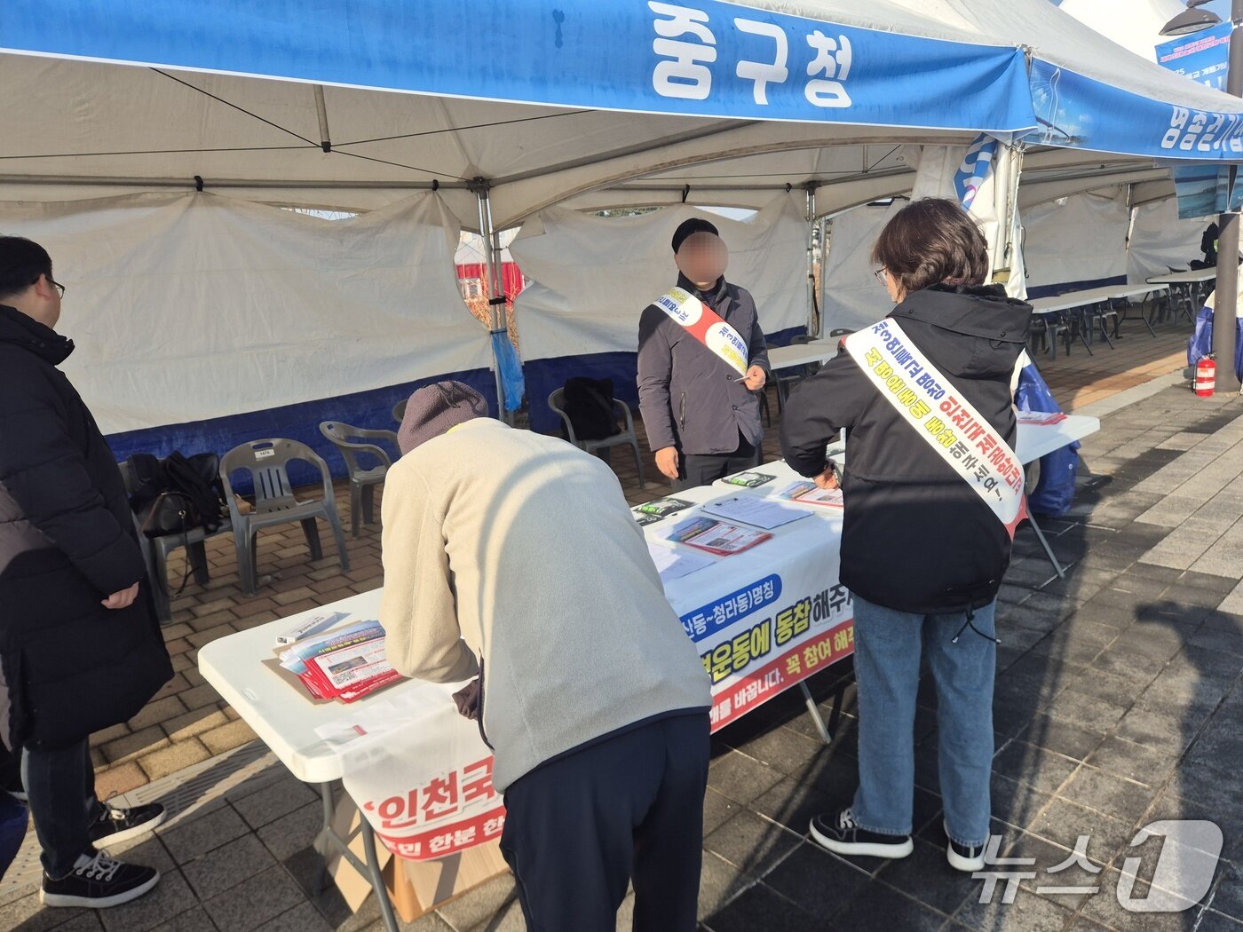 본문 이미지 -  인천 중구청이 마련한 부스에 한 시민이 방문해 인천국제공항대교 서명운동에 동참하고 있다./뉴스1