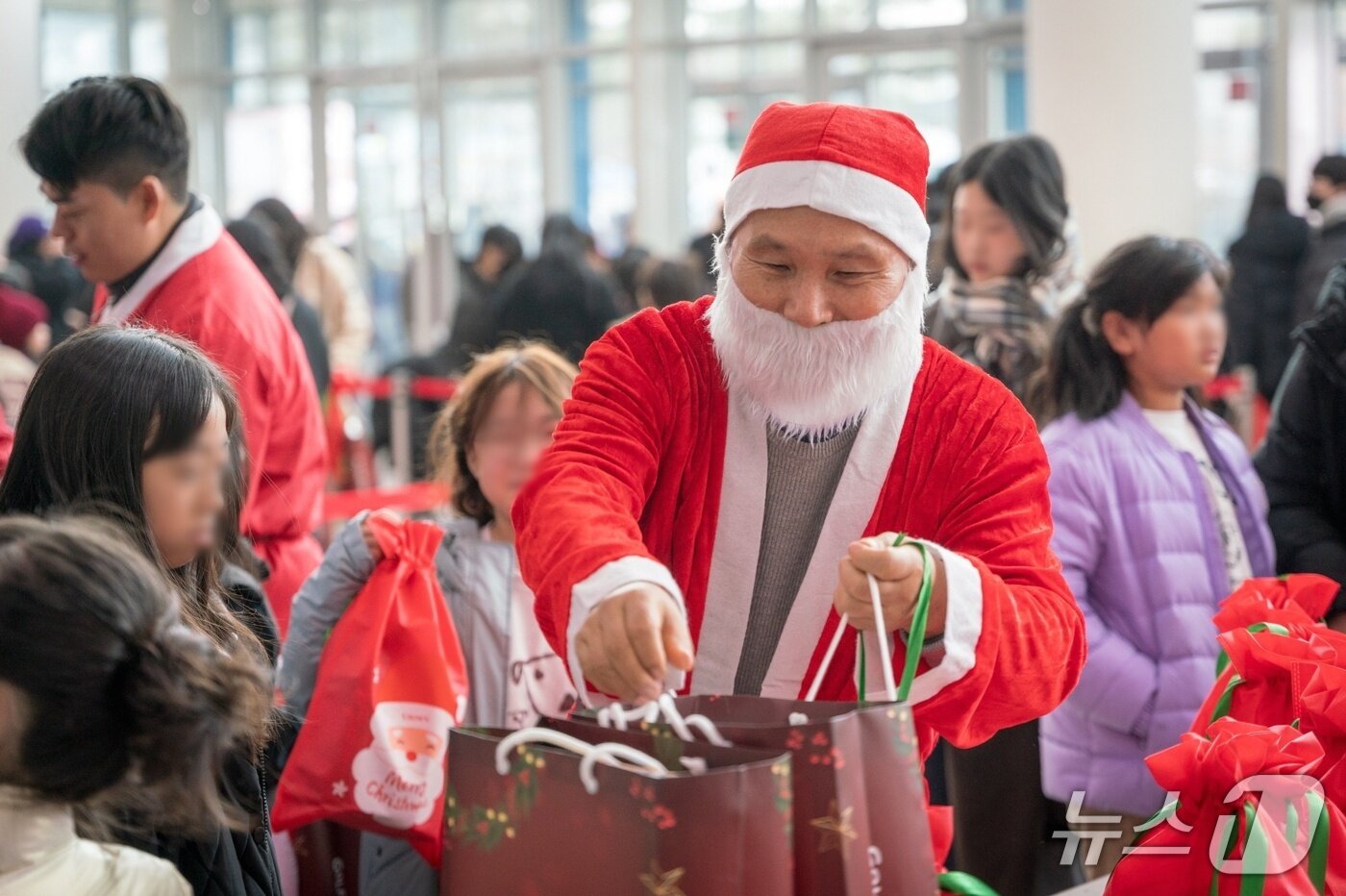 본문 이미지 - 골프존문화재단이 6일 충남대학교 정심화국제문화회관 정심화홀에서 2025 희망행복나눔 페스티벌&#39;을 진행했다. 산타복장을 한 김영찬 이사장이 아이들에게 선물을 나눠주고 있는 모습. &#40;골프존 제공&#41;