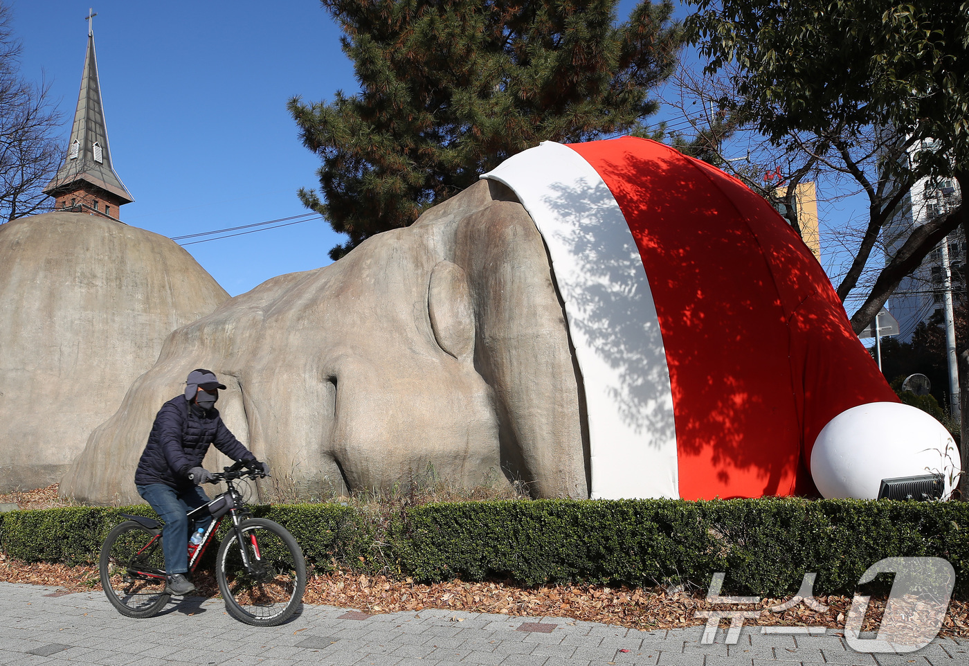 (대구=뉴스1) 공정식 기자 = 포근한 겨울 날씨를 보인 8일 대구 달서구 선사유적공원 진입로에 설치된 거대 원시인 석상 이만옹(二萬翁) 머리에 산타 모자가 설치돼 크리스마스가 다 …