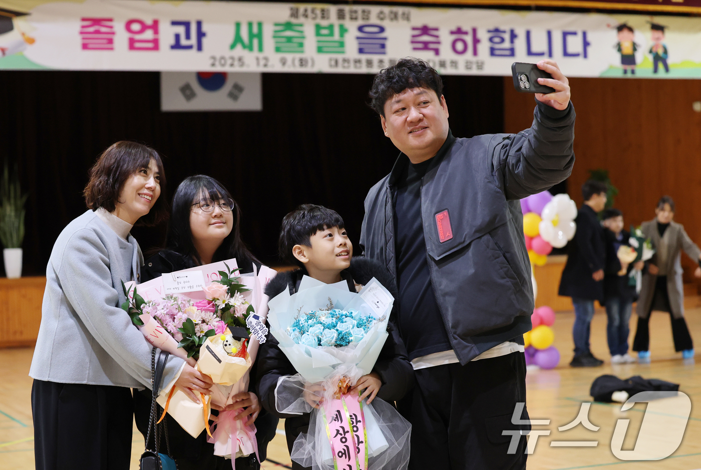 (대전=뉴스1) 김기태 기자 = 9일 대전 서구 변동초등학교에서 열린 졸업식에서 졸업생이 꽃다발을 들고 가족과 사진촬영을 하고 있다. 2025.12.9/뉴스1