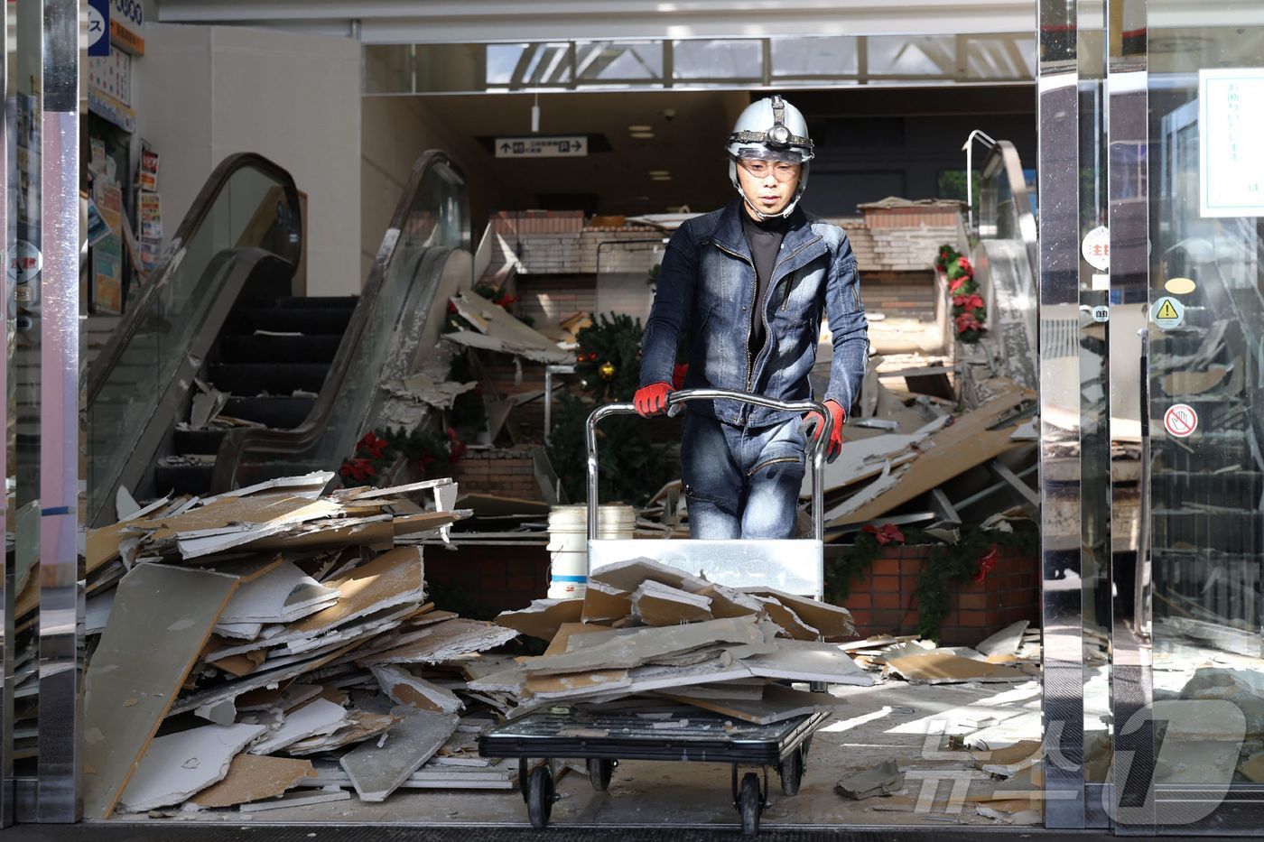 하치노헤 (AFP=뉴스1) 이정환 기자 = 9일 일본 동북부 아오모리현 하치노헤에서 지진으로 피해를 입은 쇼핑센터에서 한 노동자가 잔해를 치우고 있다. 2025.12.09.ⓒ AF …