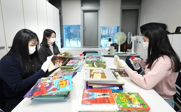 본문 이미지 - 한국P&G 팸퍼스 임직원들이 리모델링된 대기 공간에서 소아 환자를 위한 동화책을 소독하고 있다. (사진=한국P&G 제공)