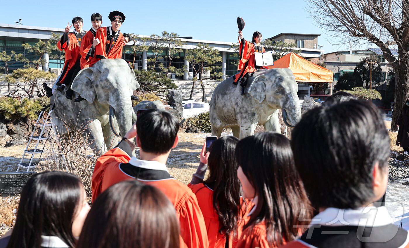 본문 이미지 - 13일 서울 중구 장충동 동국대학교에서 열린 &#39;2025년 봄 학위수여식&#39;에서 졸업생들이 코끼리 동상에 올라타 기념촬영을 하고 있다. 2025.2.13/뉴스1 ⓒ News1 김도우 기자