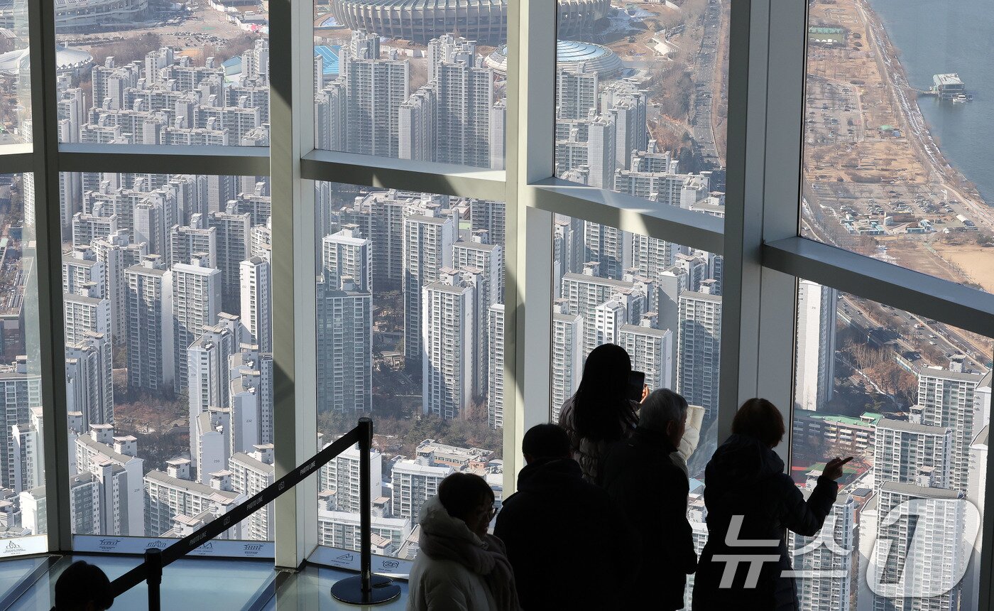 본문 이미지 - 13일 서울 송파구 롯데월드타워 서울스카이를 찾은 관람객이 잠실 아파트단지를 바라보고 있다. 2025.2.13/뉴스1 ⓒ News1 박세연 기자