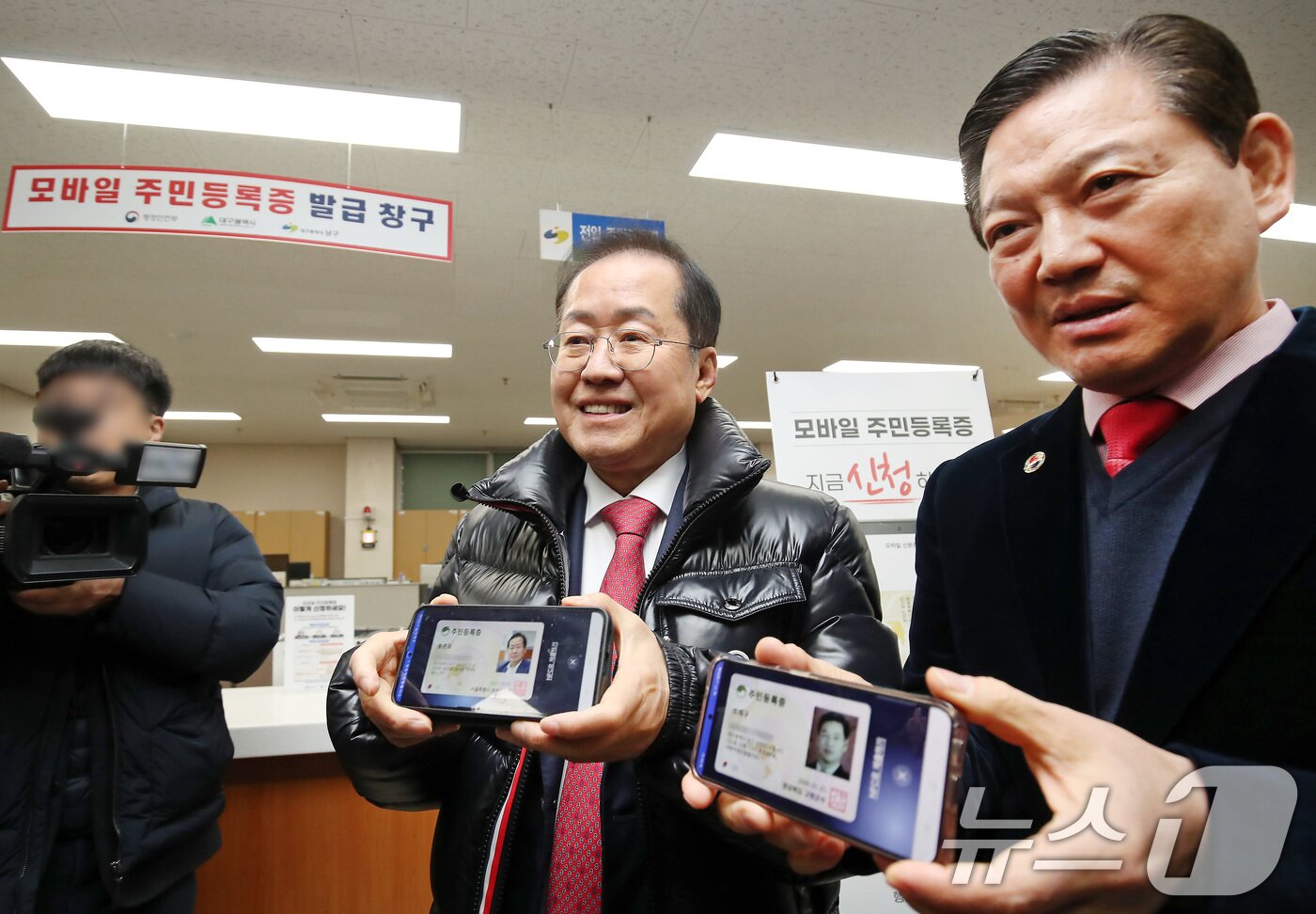 본문 이미지 - 홍준표 대구시장(왼쪽)과 조재구 남구청장이 14일 오전 대구 남구 봉덕2동 행정복지센터를 방문해 모바일 주민등록증을 발급받은 뒤 취재진에게 보여주고 있다. 2025.2.14/뉴스1 ⓒ News1 공정식 기자