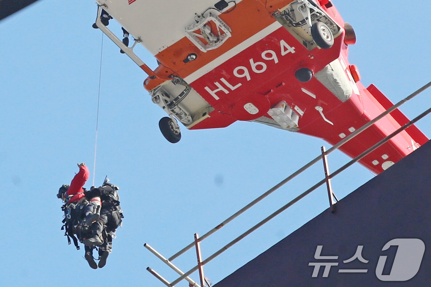 본문 이미지 - 14일 부산 기장군 반얀트리 호텔 신축 공사장에서 화재가 발생해 소방대원들이 헬기를 동원해 옥상에 있던 인부를 구조하고 있다. 2025.2.14/뉴스1 ⓒ News1 윤일지 기자