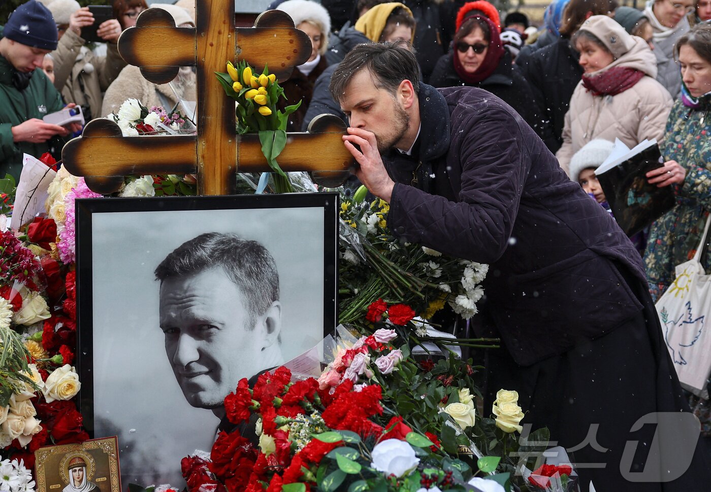 본문 이미지 - 16일(현지시간) 러시아 모스크바 보리솝스코예 묘지에 있는 알렉세이 나발니의 묘지에서 시민들이 나발니 사망1주기를 추모하고 있다.  ⓒ 로이터=뉴스1