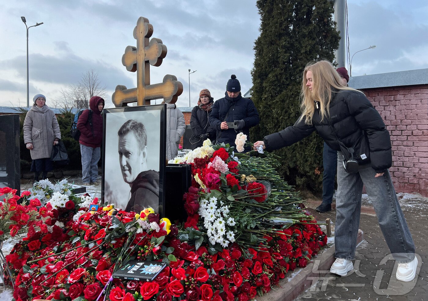 본문 이미지 - 16일(현지시간) 러시아 모스크바 보리솝스코예 묘지에 있는 알렉세이 나발니의 묘지에서 시민들이 나발니 사망1주기를 추모하고 있다.  ⓒ 로이터=뉴스1