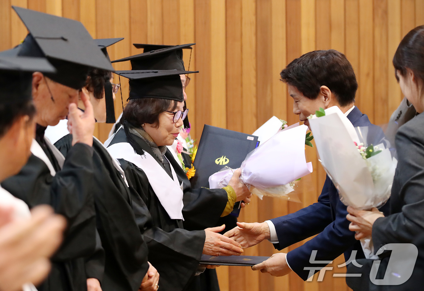 (대구=뉴스1) 공정식 기자 = 19일 오전 대구 달서구 노인종합복지관에서 열린 '제20기 달서구노인복지대학 졸업식'에 참석한 졸업생들이 이태훈 달서구청장으로부터 졸업장과 꽃다발을 …