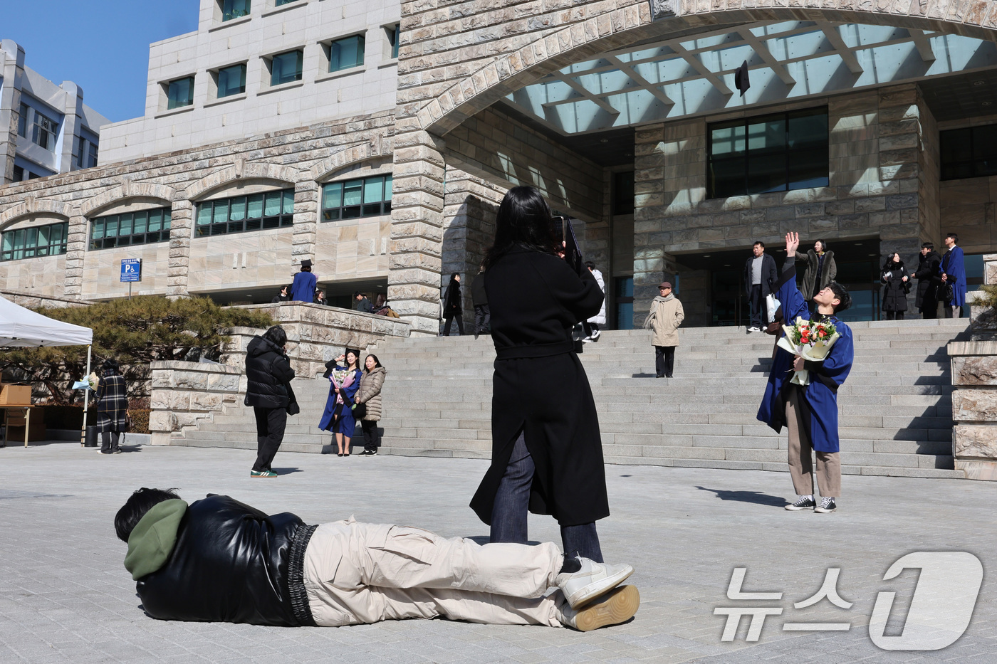 (서울=뉴스1) 신웅수 기자 = 20일 서울 성동구 한양대학교에서 열린 전기 학위수여식에서 한 학생이 누워서 졸업생의 사진을 찍어주고 있다. 2025.2.20/뉴스1