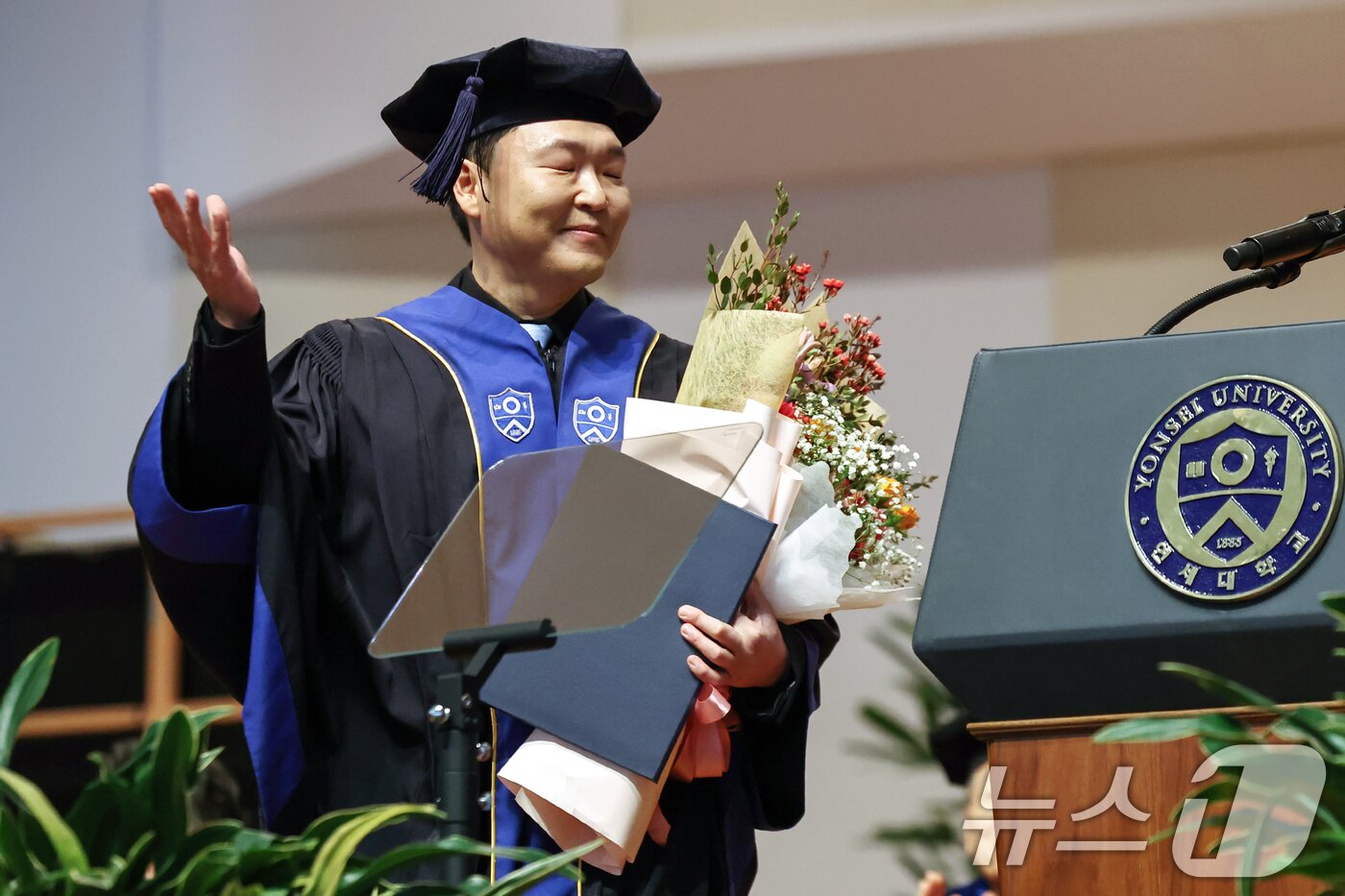 본문 이미지 - 가수 싸이(박재상)가 24일 서울 서대문구 연세대학교 대강당에서 열린 학위수여식에서 윤동섭 총장으로부터 명예졸업증서를 받은 뒤 졸업생들의 호응을 유도하고 있다. 2025.2.24/뉴스1 ⓒ News1 민경석 기자