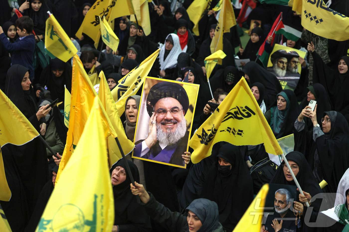 본문 이미지 - 레바논의 친이란 무장 정파 헤즈볼라의 오랜 수장이었던 하산 나스랄라의 장례식에서 25일&#40;현지시간&#41; 조문객들이 헤즈볼라 깃발과 나스랄라의 사진을 들고 그를 추모하고 있다. 2025.2.25 ⓒ AFP=뉴스1 ⓒ News1 강민경 기자