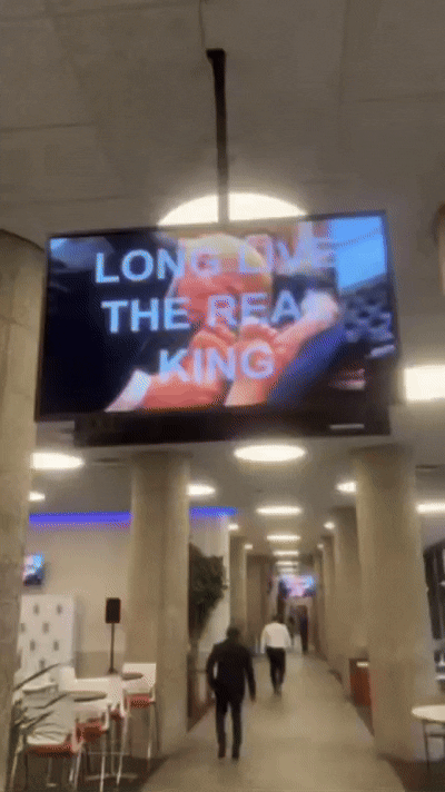 본문 이미지 - 인공지능(AI)이 제작한 트럼프 대통령이 머스크 발에 키스하는 영상이 미국 주택도시개발부(HUD) 본부에서 재생되고 있다. (출처=레이첼 코헨 복스 기자 엑스) 2025.2.25./뉴스1