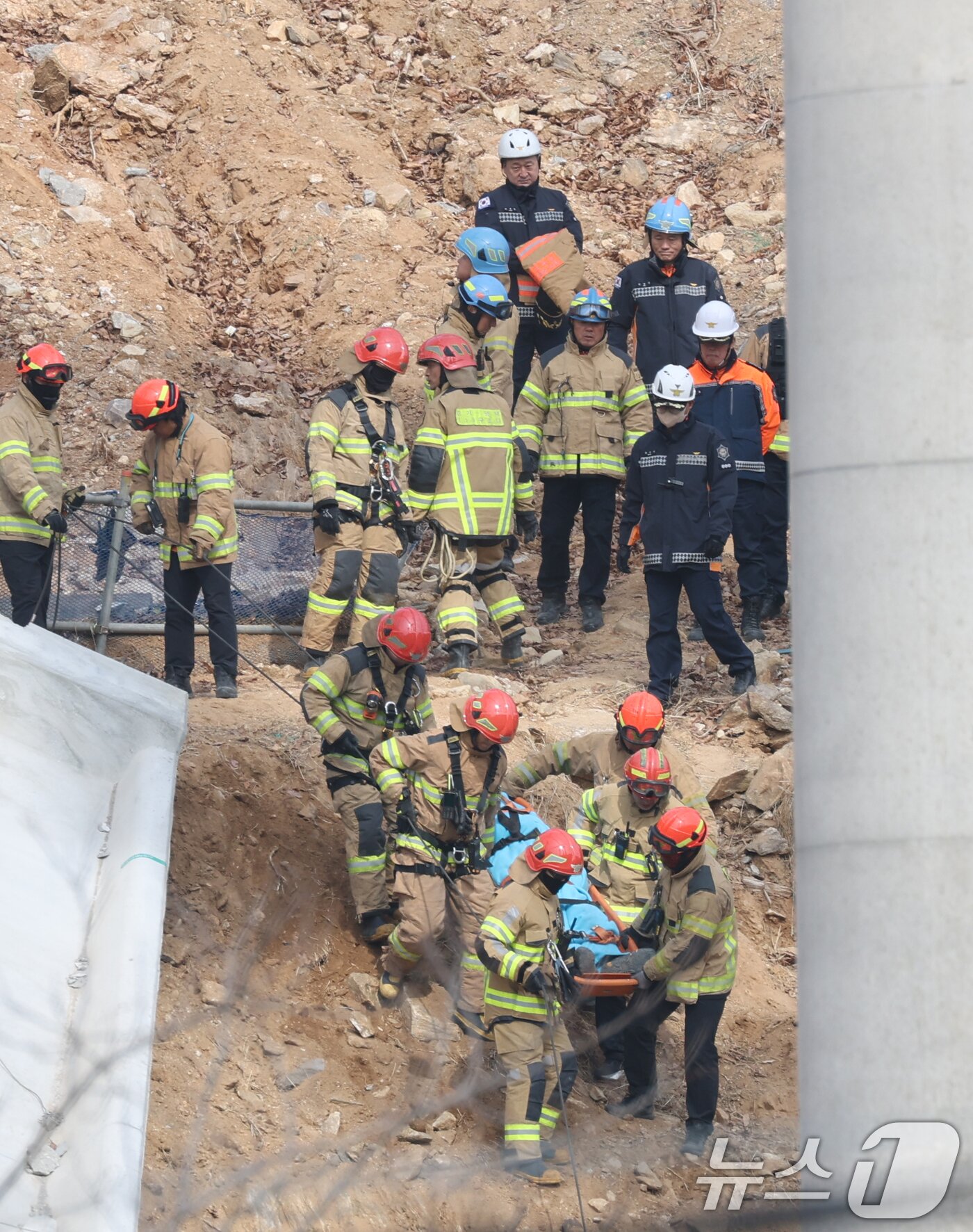 본문 이미지 - 25일 경기 안성시 서운면 산평리 서울-세종고속도로 다리 건설현장에서 철근 구조물이 교각 아래로 떨어져 소방관들이 수색 작업을 마친 뒤 매몰자를 이송하고 있다. 이번 사고로 작업자 10명이 매몰되는 사고가 발생, 4명이 사망했다. 2025.2.25/뉴스1 ⓒ News1 김영운 기자