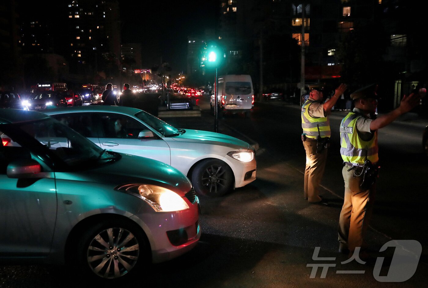 본문 이미지 - 25일(현지시간) 칠레에 대규모 정전 사태가 발생한 가운데 비냐 델 마르에서 경찰이 차량 헤드라이트 불빛을 비춘 채 교통수신호를 보내고 있다. 2025.02.25 ⓒ 로이터=뉴스1 ⓒ News1 최종일 선임기자