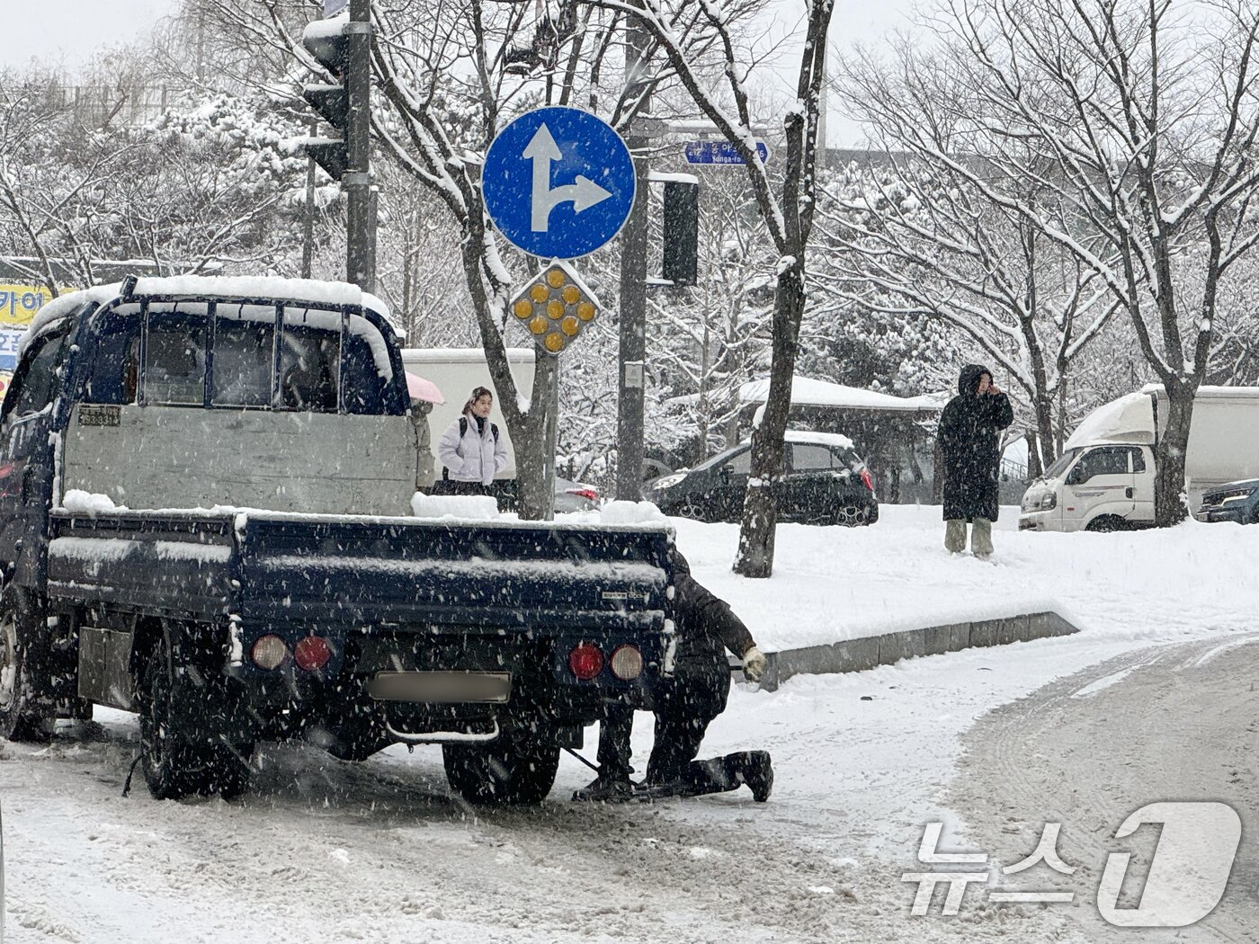 본문 이미지 - 대설주의보가 발효 중인 4일 오전 광주 광산구 한 도로에서 빙판길에 빠진 1톤 트럭 운전자가 밧줄로 뒷바퀴를 고정시키고 있다. 2025.2.4/뉴스1 ⓒ News1 이승현 기자