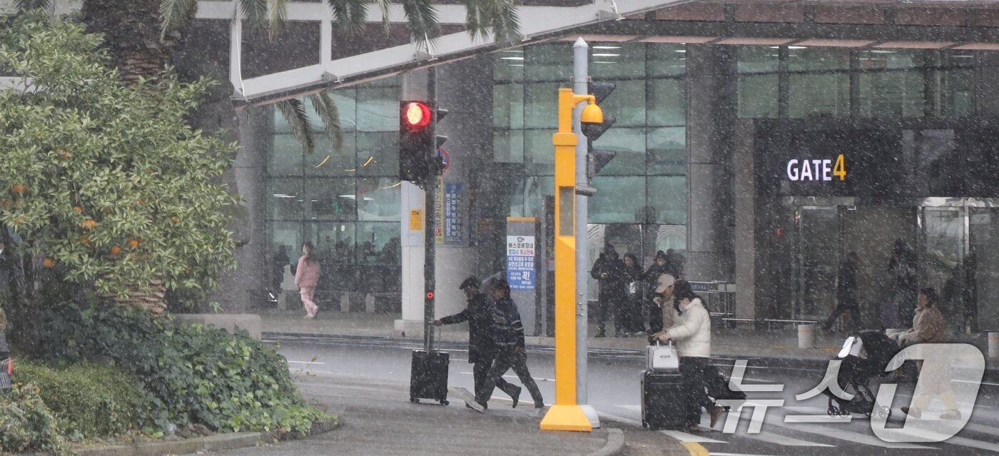 본문 이미지 - 7일 오후 눈보라가 치는 제주국제공항에서 관광객들이 횡단보도를 건너고 있다. 이날 제주는 강풍과 많은 눈으로 항공편 운항이 차질을 빚고 있다. 2025.2.7/뉴스1 ⓒ News1 고동명 기자