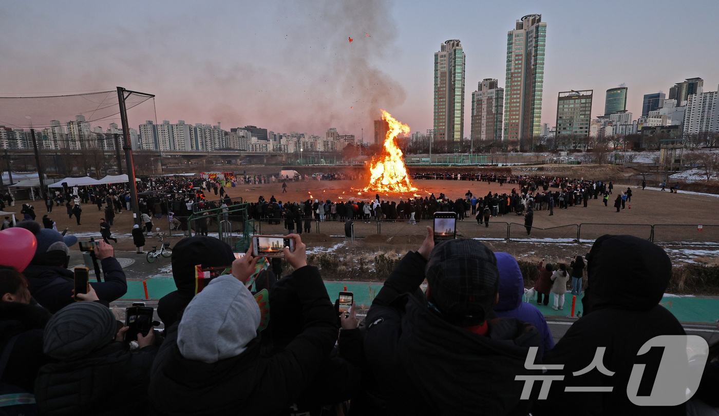 (서울=뉴스1) 장수영 기자 = 8일 오후 서울 양천구 안양천 신정교 일대에서 열린 ‘제23회 양천구 정월대보름 민속 축제’를 찾은 시민들이 달집태우기를 관람하며 안녕과 건강을 기 …