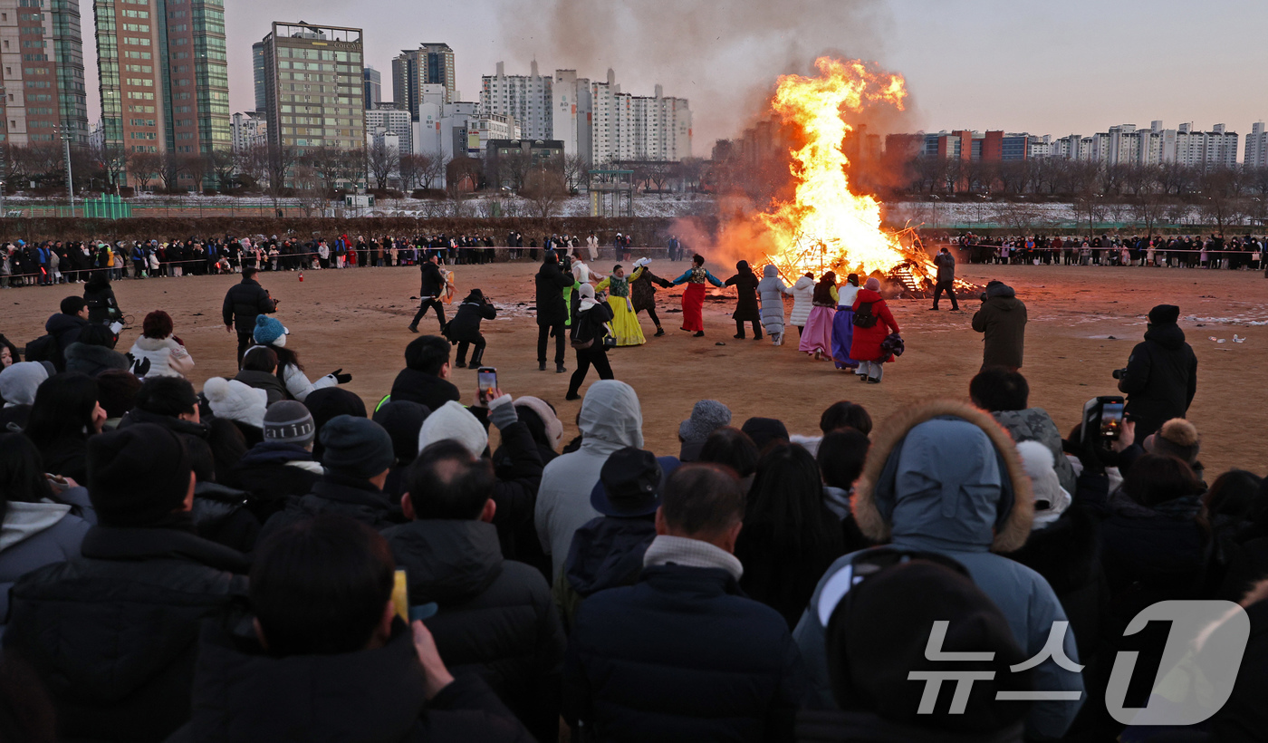 (서울=뉴스1) 장수영 기자 = 8일 오후 서울 양천구 안양천 신정교 일대에서 열린 ‘제23회 양천구 정월대보름 민속 축제’를 찾은 시민들이 달집태우기를 관람하며 안녕과 건강을 기 …