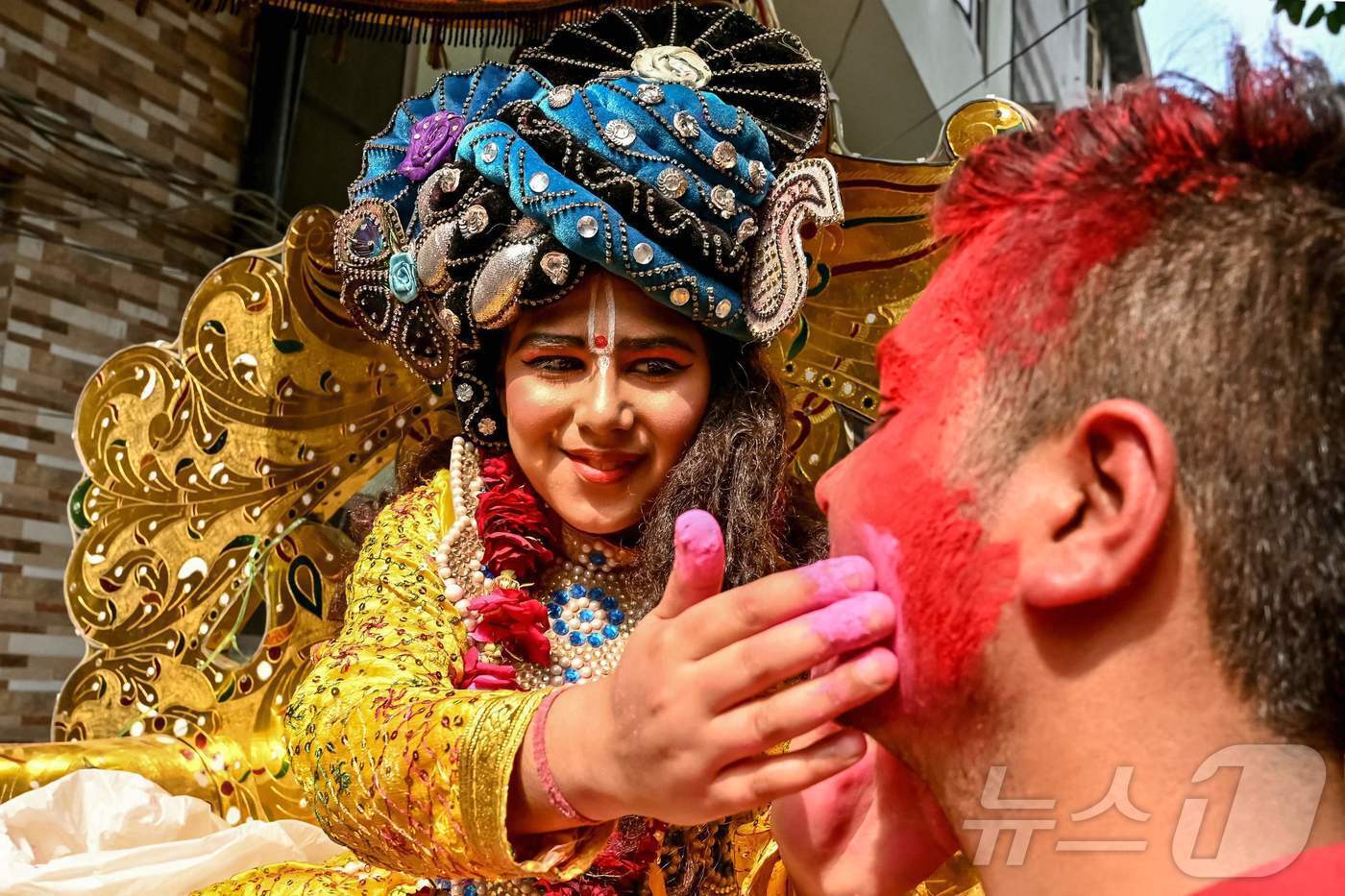 본문 이미지 - 10일(현지시간) 인도 암리차르에서 힌두교의 봄 축제 인 홀리 축제에 앞서 열린 종교 행렬에서 힌두교 신 크리슈나로 분장한 예술가가 신도를 색으로 칠하고 있습니다.ⓒ AFP=뉴스1