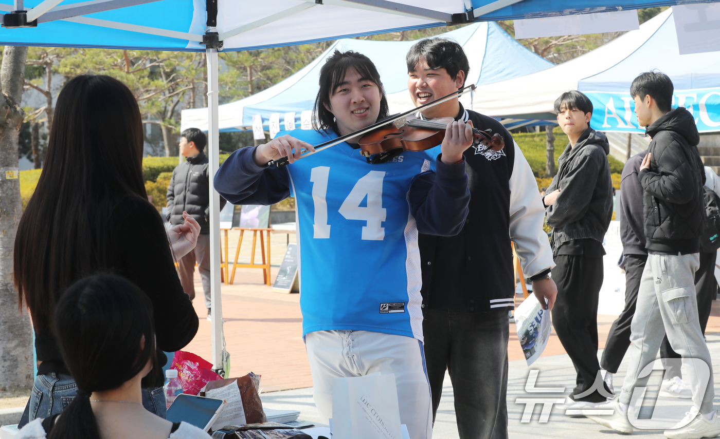 (부산=뉴스1) 윤일지 기자 = 11일 부산 금정구 부산대학교 시월광장에서 열린 동아리 신입 회원 모집 행사에서 미식축구 동아리 회원이 오케스트라 동아리 체험을 하고 있다. 202 …