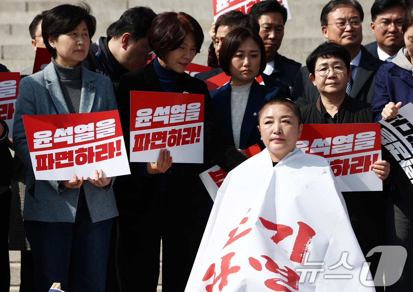 (서울=뉴스1) 김민지 기자 = 더불어민주당 의원들이 11일 오후 서울 여의도 국회 본청 앞에서 열린 윤석열 대통령 조기 파면 촉구 삭발식에서 삭박을 마친 전진숙 의원을 격려하고 …