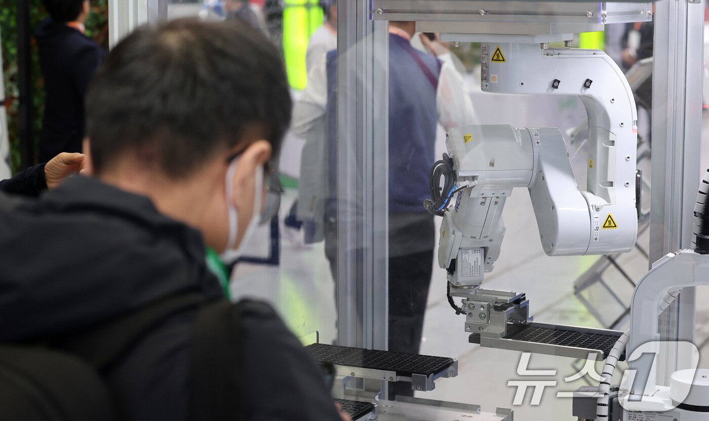 본문 이미지 - 12일 서울 강남구 코엑스에서 열린 2025 스마트공장·자동화산업전를 찾은 한 관람객이 로봇을 활용한 반도체 검사 공정을 살펴보고 있다. 2025.3.12/뉴스1 ⓒ News1 김성진 기자