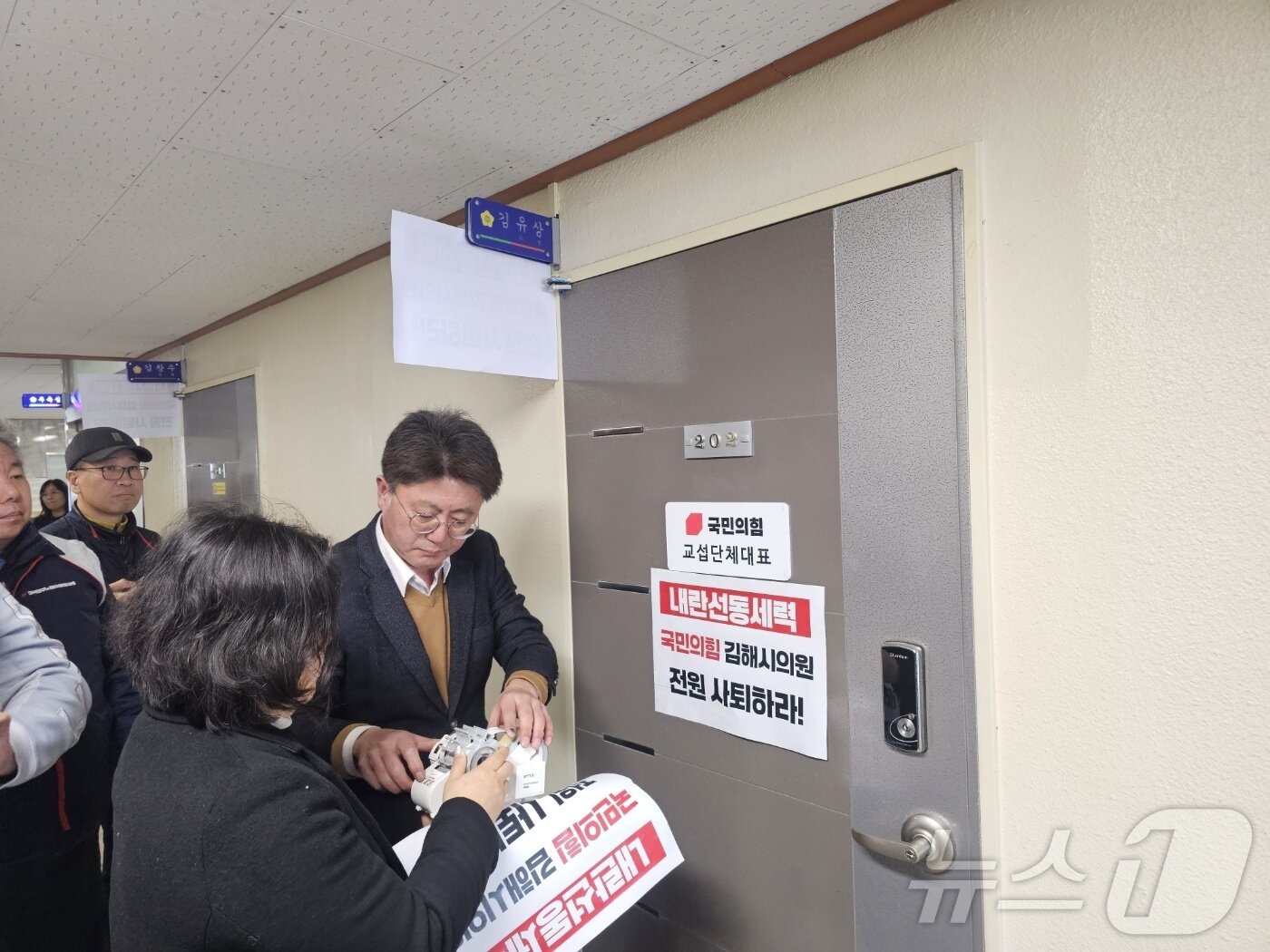 본문 이미지 - 윤석열 퇴진 김해시민연대가 19일 김해시의회를 찾아 &#39;탄핵 각하 촉구 결의안&#39;을 대표 발의안 국민의힘 김유상 의원 사무실에 사퇴를 촉구하는 손피켓을 붙이고 있다. ⓒ 뉴스1 박민석 기자