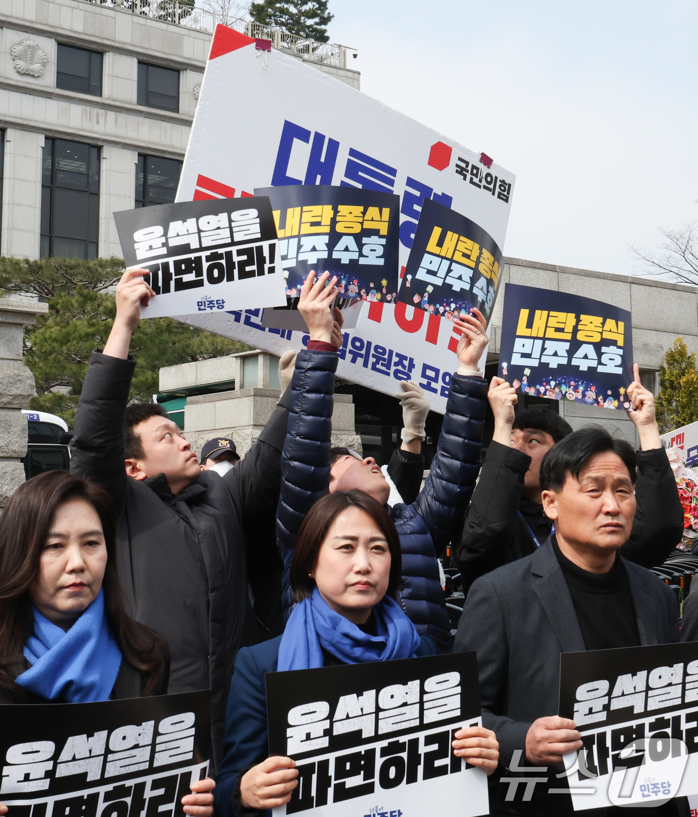 (서울=뉴스1) 허경 기자 = 20일 서울 종로구 헌법재판소 앞에서 열린 극우 폭력 사태 규탄 기자회견에서 더불어민주당 보좌관들이 손피켓으로 대통령 탄핵 각하 피켓을 막고 있다. …