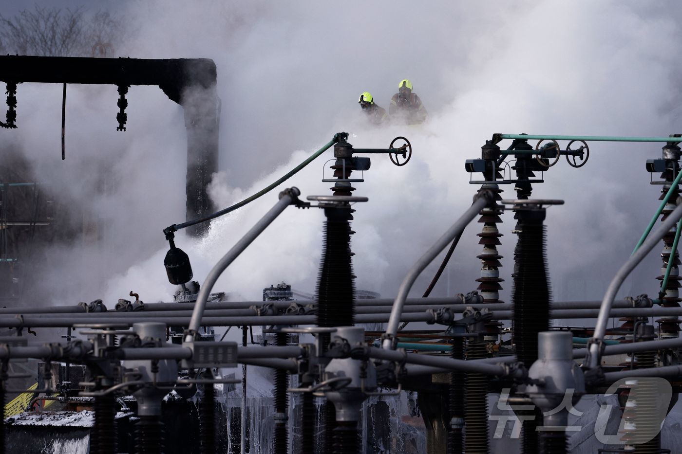 (런던 AFP=뉴스1) 우동명 기자 = 21일(현지시간) 영국 런던 히스로 공항 인근 변전소에서 화재가 발생해 연기가 솟아 오르는 현장서 소방대원이 진화를 하고 있다. 2025.0 …