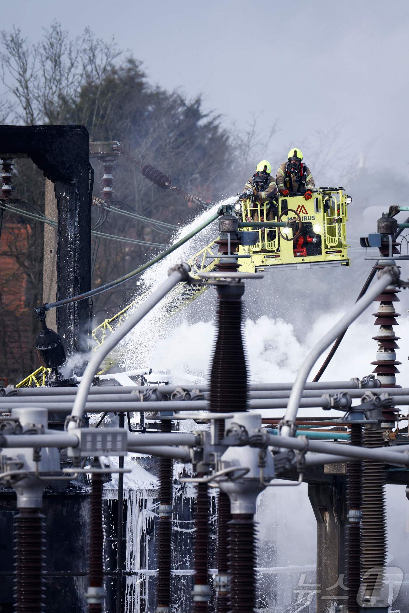 (런던 AFP=뉴스1) 우동명 기자 = 21일(현지시간) 영국 런던 히스로 공항 인근 변전소에서 화재가 발생해 연기가 솟아 오르는 현장서 소방대원이 진화를 하고 있다. 2025.0 …