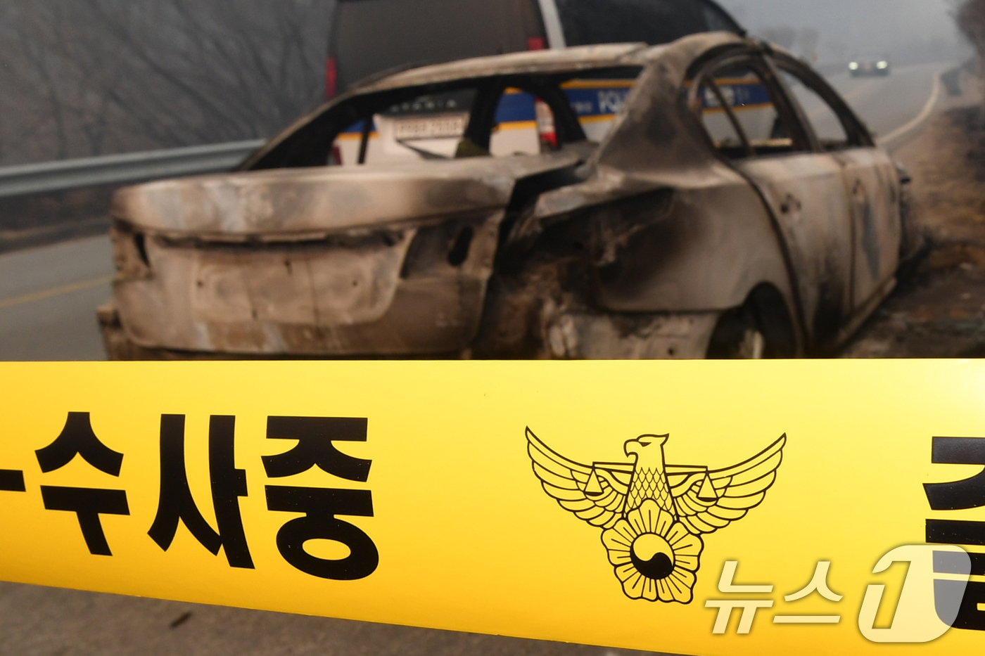(영덕=뉴스1) 최창호 기자 = 26일 경북 영덕군 매정리 마을로 들어가는 도로에서 경찰관이 불에 탄 승용차를 확인하고 있다.경찰은 산불이 확산되자 승용차로 대피하던 요양원 입소자 …
