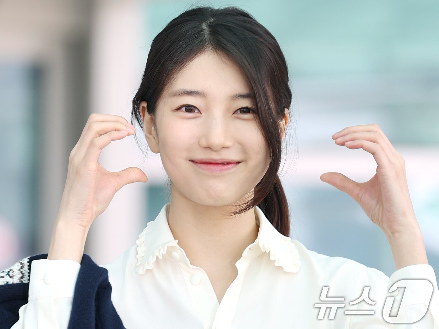 본문 이미지 - 배우 수지가 해외 일정을 위해 26일 인천국제공항을 통해 싱가포르로 출국하기 전 볼 하트로 인사를 전하고 있다. ⓒ News1 권현진 기자
