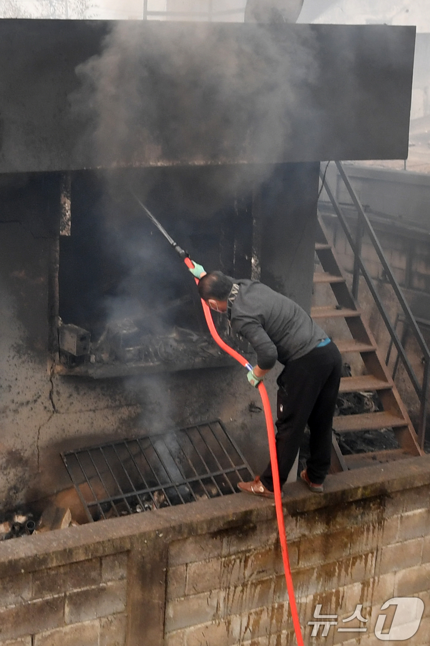 (영덕=뉴스1) 최창호 기자 = 경북 의성 산불이 강풍을 타고 영덕으로 확산된 26일 오전 영덕읍 매정 1리 마을에서 주민이 주택에 님아 있는 불을 끄고 있다. 2025.3.26/ …