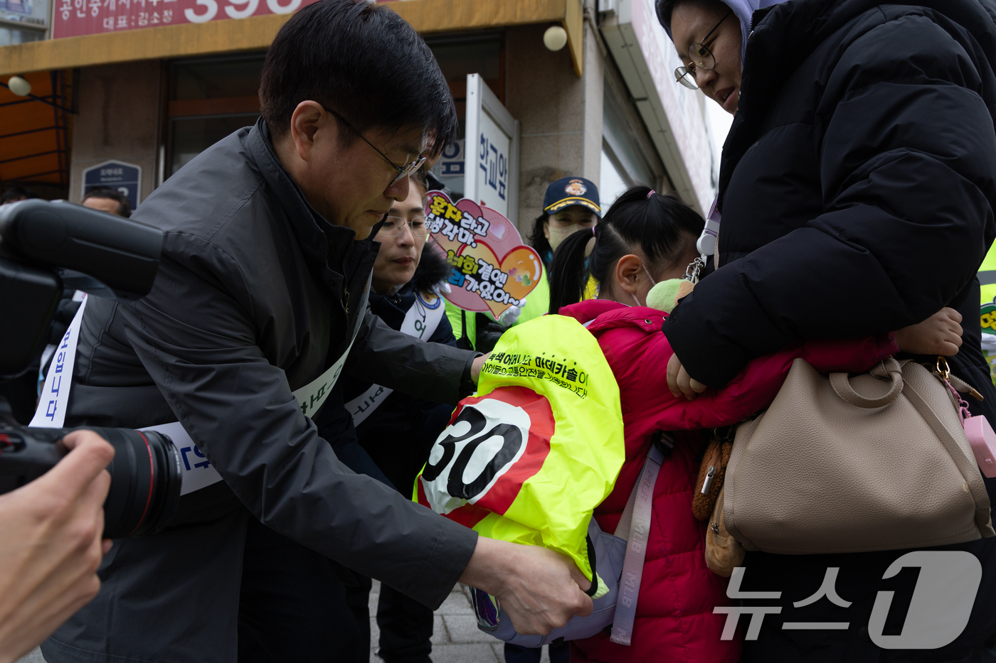 (서울=뉴스1) 이승배 기자 = 5일 오전 서울 서대문구 고은초등학교앞에서 열린 신학기 안전한 학교 만들기 캠페인에서 관계자가 학생에게 스쿨존 속도제한 레인커버를 씌워주고 있다. …