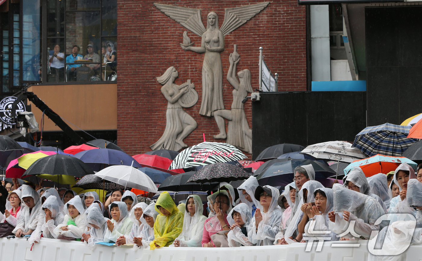 (서울=뉴스1) 송원영 기자 = 18일 오전 서울 명동성당 앞에서 카톨릭 신자들이 '평화와 화해의 미사'에서 외부 모니터로 교황의 모습을 보며 기도를 하고 있다.프란치스코 교황은 …