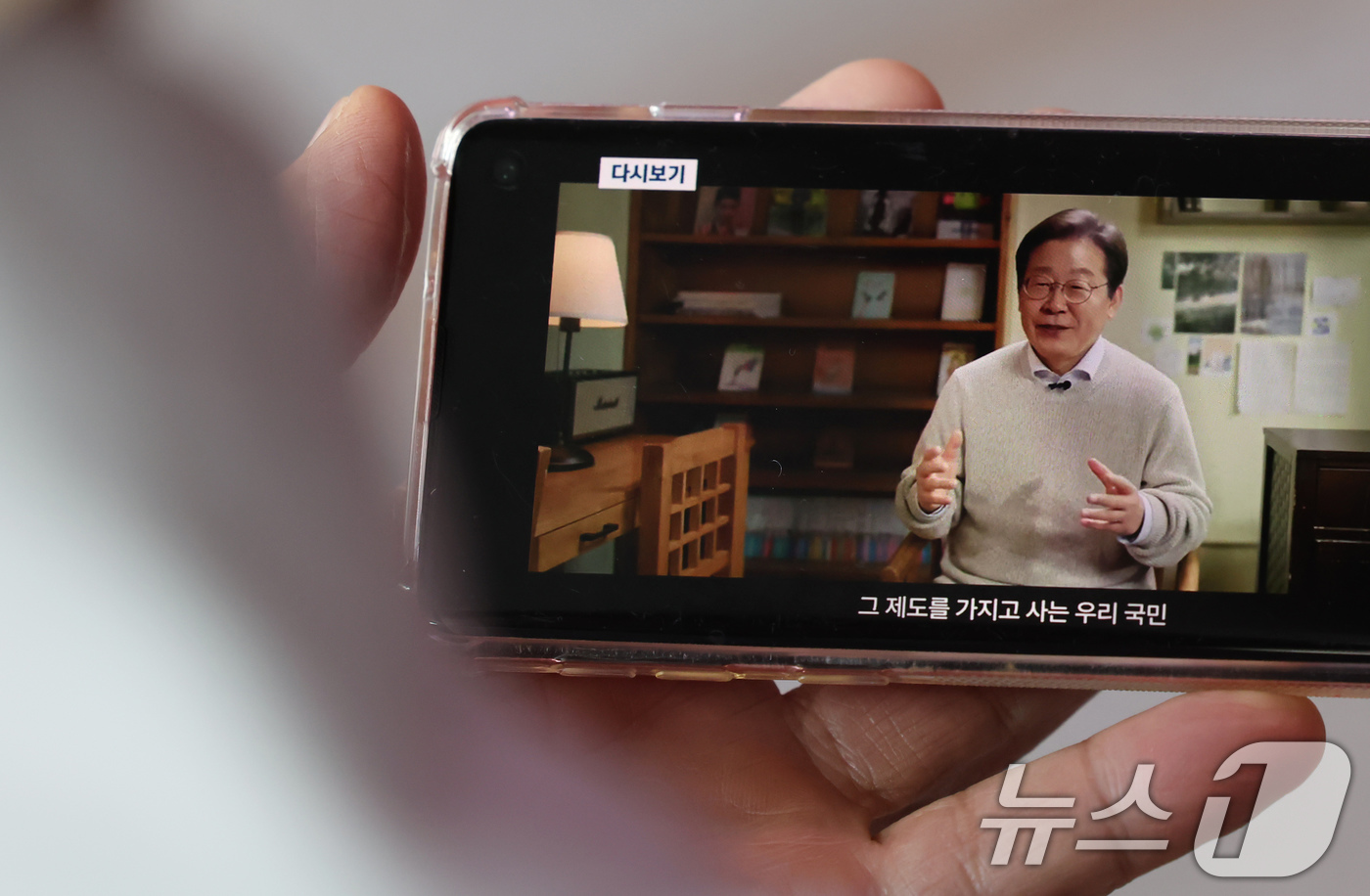 (서울=뉴스1) 장수영 기자 = 10일 오전 서울 중구 서울역을 찾은 시민이 스마트폰을 통해 이재명 전 더불어민주당 대표의 대통령 선거 출마 선언 영상을 바라보고 있다. 2025. …