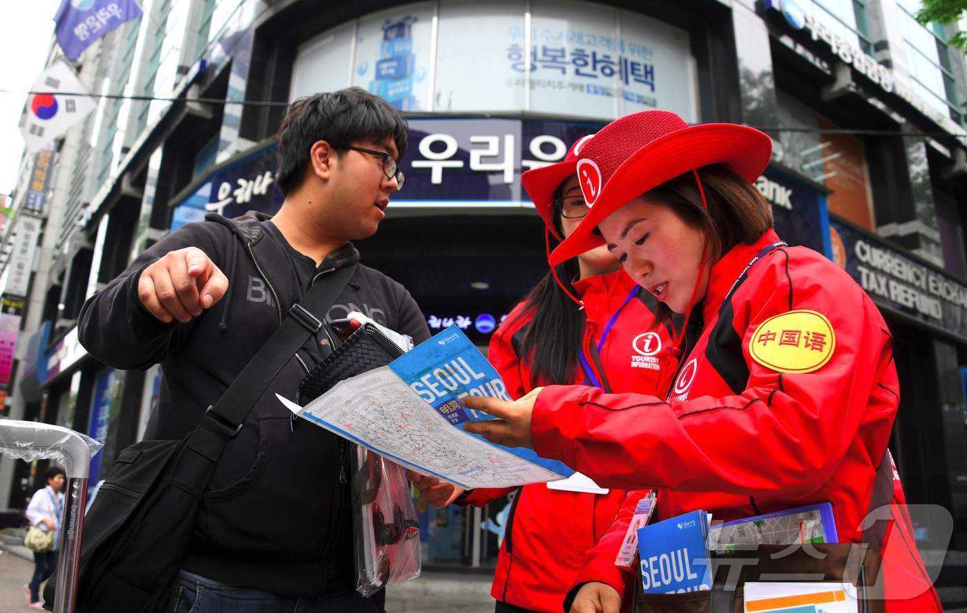 본문 이미지 - 서울의 명동에서 한 중국인에게 관광안내원이 길을 알려주고 있다. ⓒ AFP=뉴스1