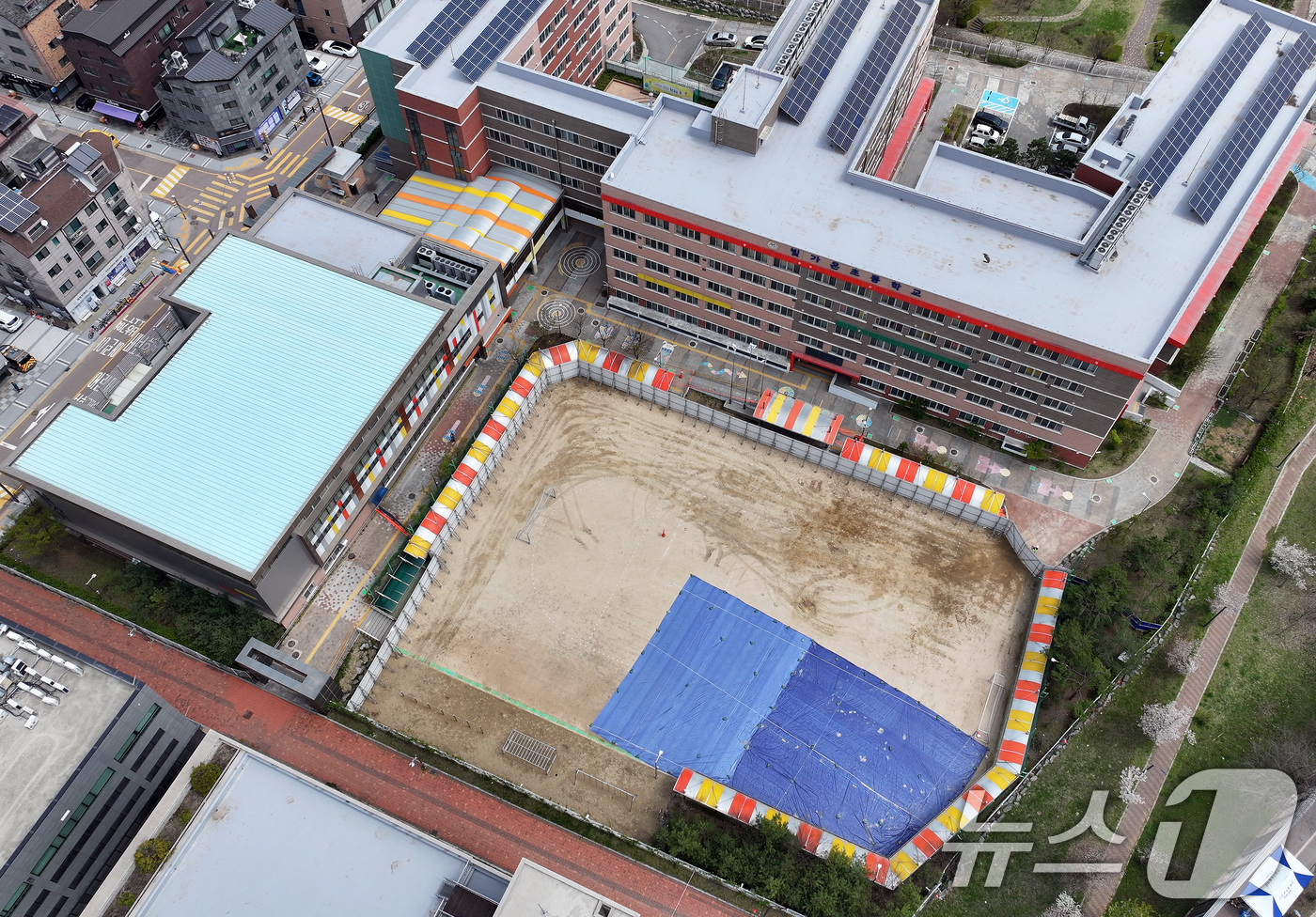 (광명=뉴스1) 이동해 기자 = 16일 경기 광명시 일직동 신안산선 복선전철 5-2공구 붕괴 현장 인근에 위치한 초등학교 운동장에 균열 부위 방수포가 깔려 있다. 2025.4.16 …