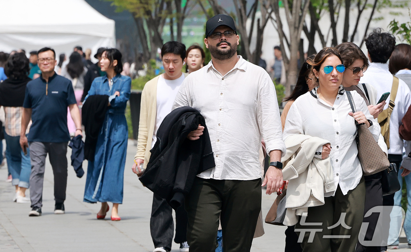 (서울=뉴스1) 김진환 기자 = 서울의 낮 최고기온이 20도를 기록하는 등 완연한 봄날씨를 보인 18일 오후 서울 종로구 광화문광장을 찾은 외국인 관광객들이 외투를 든 채 발걸음을 …
