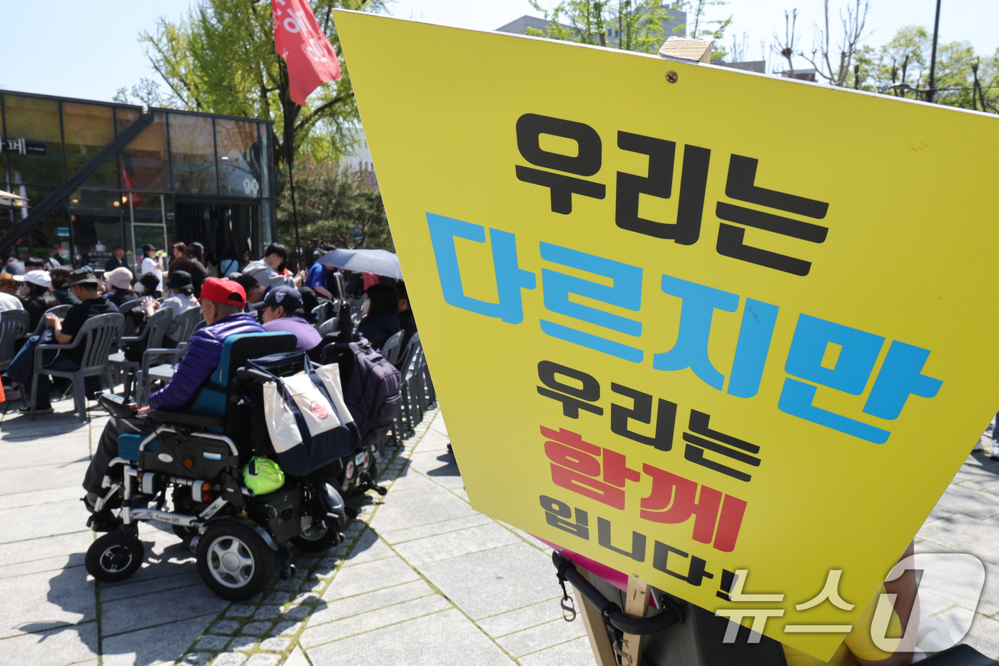 (서울=뉴스1) 신웅수 기자 = 20일 오후 서울 종로구 마로니에 공원에서 장애인의 날을 맞아 열린 전국장애인차별철폐연대 전국집중결의대회에서 한 참가자가 전동휠체어에 피켓을 걸고 …