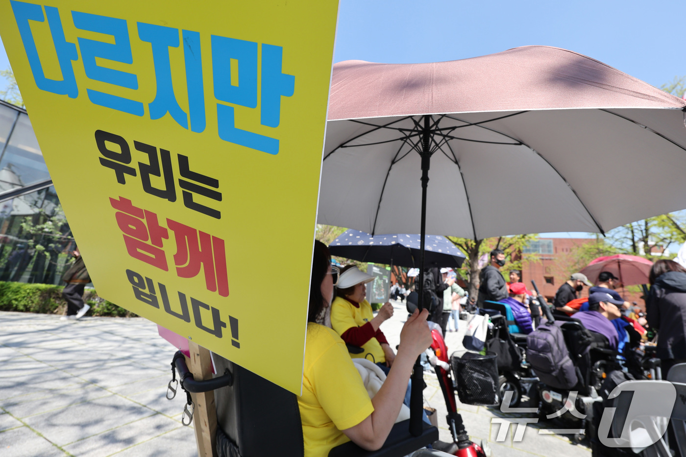 (서울=뉴스1) 신웅수 기자 = 20일 오후 서울 종로구 마로니에 공원에서 장애인의 날을 맞아 열린 전국장애인차별철폐연대 전국집중결의대회에서 한 참가자가 전동휠체어에 피켓을 걸고 …