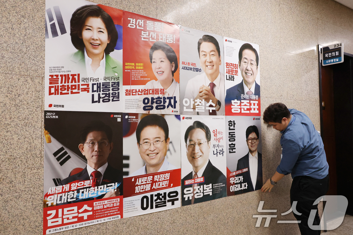 (서울=뉴스1) 이광호 기자 = 20일 오후 서울 여의도 국회 본청 국민의힘 사무실 앞 벽면에 당 관계자가 대선 경선 후보자 포스터를 붙이고 있다. 2025.4.20/뉴스1