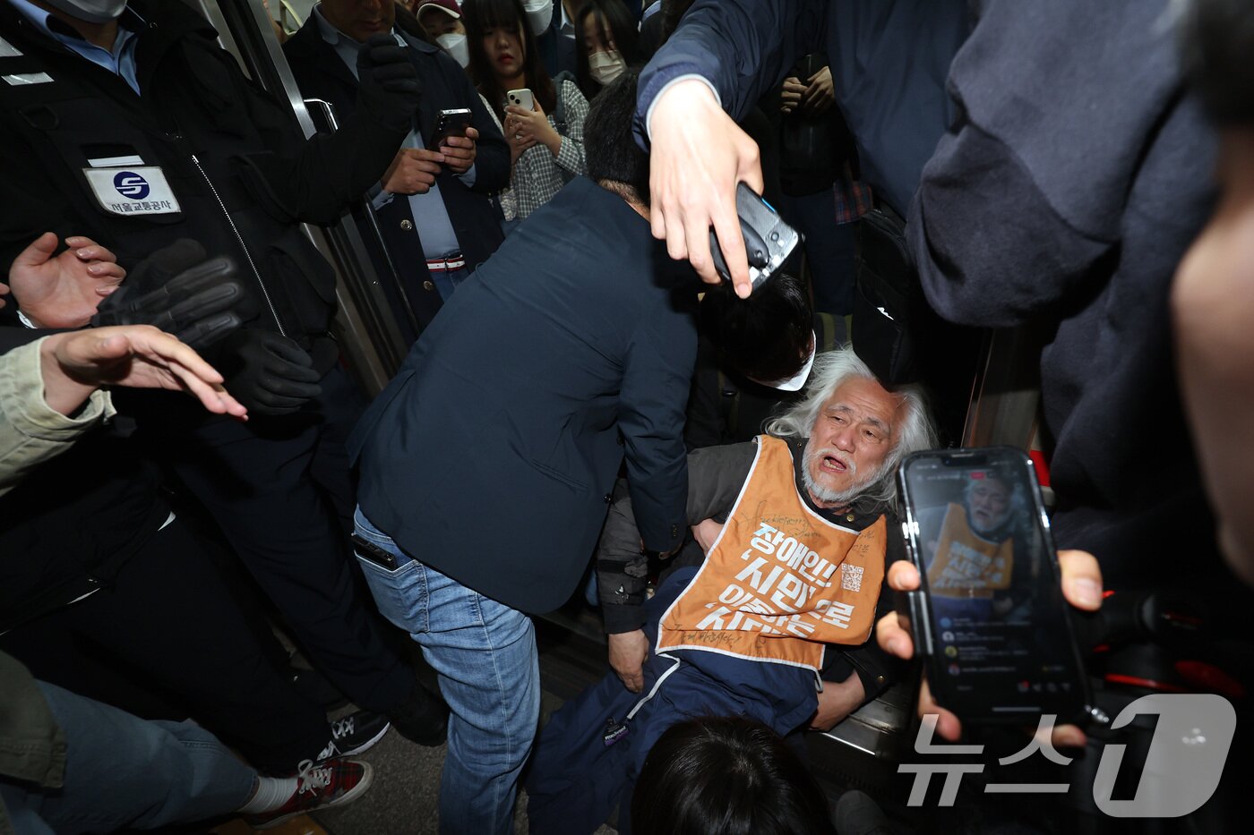 본문 이미지 - 박경석 전국장애인차별철폐연대&#40;전장연&#41; 대표가 21일 서울 지하철 4호선 혜화역 동대문 방면 승강장에서 제62차 &#39;출근길 지하철 탑니다&#39; 시위를 벌이던 중 이를 저지하던 경찰·서울교통공사 직원 등과 충돌하며 열차 입구에 넘어져 있다. 2025.4.21/뉴스1 ⓒ News1 이동해 기자